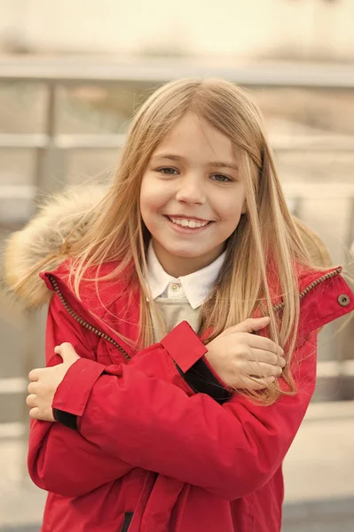 Niño niña sonriente usar chaqueta de abrigo con piel en la capucha, pero se siente frío. Concepto de clima frío. Se está congelando. Bebé abrazarse a sí misma debido al clima frío. Chico tratar de calentar al aire libre. Otoño invierno estación fría — Foto de Stock