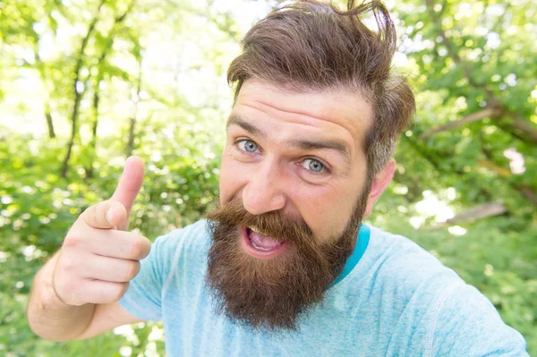 Hipster with long beard emotional face close up nature background. Summer fun. Bearded guy in park forest. Bearded hipster. Crazy bearded mature man in natural environment. Brutal male leisure