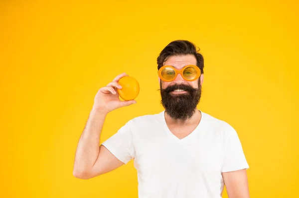 Fresco e sano. Alimentazione estiva. Hipster con barba in vena estiva. Frutta succosa. Uomo hipster barbuto in occhiali da sole arancioni su sfondo giallo. Un ragazzo allegro con la frutta matura. Vacanze estive — Foto Stock