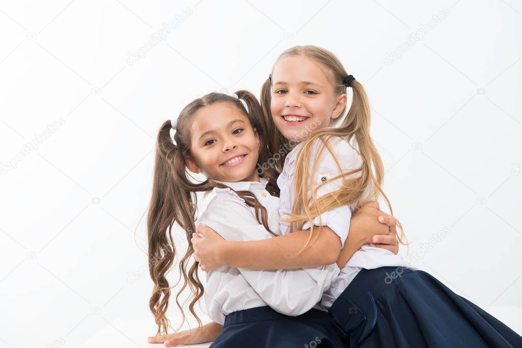 Sincere kids. Kids schoolgirls happy together. True friendship. Girls smiling happy faces hug each other white background. Girls children best friends hug. Happy childhood. Hug and love concept