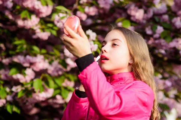 Natural cosmetics for skin. Girl in cherry flower. Kid with lipstick makeup. Small girl child in spring flower bloom. Smell of tender bloom. Sakura flower concept. Gorgeous flower and female beauty