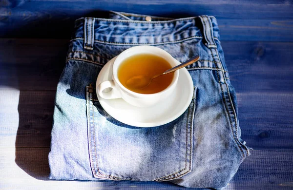 Preparazione del tè in tazza di ceramica. Foglia intera verde o nera. Abitudini sane. Il concetto dell'ora del tè. Tazza tazza di acqua calda e una bustina di tè. Tazza piena di acqua bollente e bustina di tè su sfondo jeans blu — Foto Stock