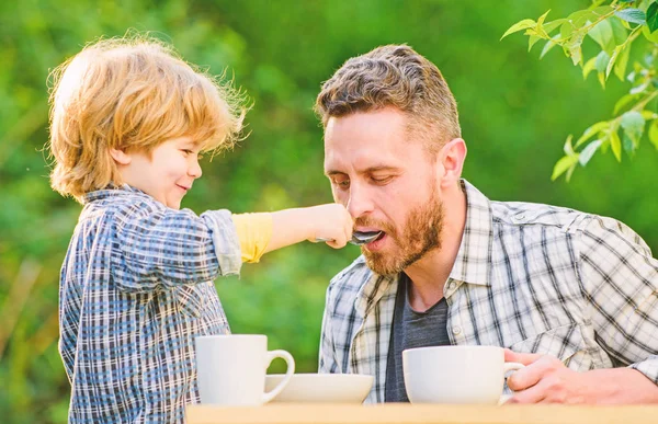 Dad and boy eat and feed each other outdoors. Ways to develop healthy eating habits. Feed your baby. Natural nutrition concept. Feeding son natural foods. Stage of development. Healthy food — Stock Photo, Image