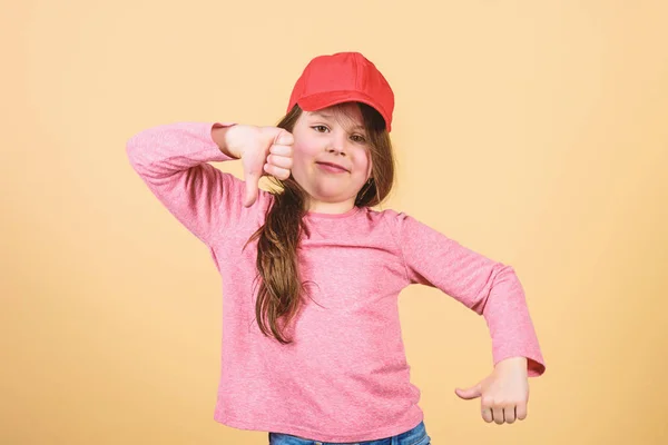 Cutie in cap. Kids fashion. Girl cute child wear cap or snapback hat beige background. Little girl wearing bright baseball cap. Modern fashion. Stylish accessory. Feeling confident with this cap