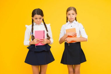 Mutsuz kitap kurtları. Sarı arka planda mutsuz küçük okul çocukları. Kitap tutan mutsuz duyguları olan sevimli küçük kızlar. Kötü işaretler yüzünden mutsuz