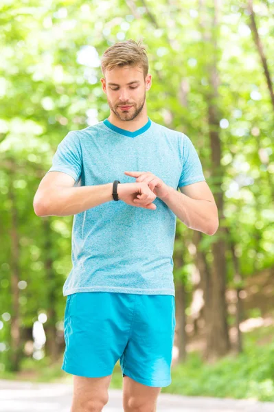 A digital sports watch. Athletic man tracking training with watch on hand. Handsome athlete using smart watch during training outdoor. Sportsman checking watch app for fitness tracking — Stock Photo, Image