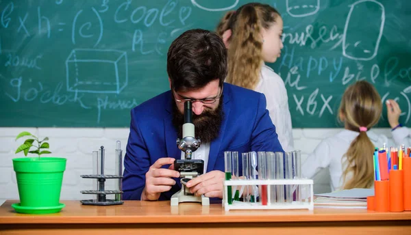 School teacher of biology. Man bearded teacher work with microscope and test tubes in biology classroom. Explaining biology to children. Biology plays role in understanding of complex forms of life
