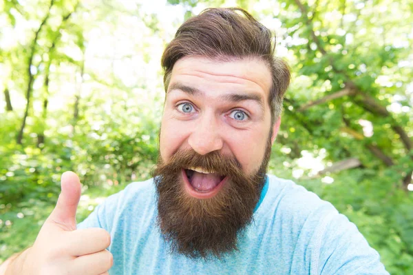 Polegares para cima para barba e barba. Homem barbudo dando polegares para cima gesto mão na paisagem natural. Um gesto hipster barbudo no dia de verão. Brutal cara vestindo bigode e barba no rosto barbudo — Fotografia de Stock