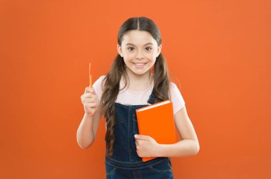 notlar yazma. çocuk günlüğü. okul kız turuncu arka plan kitap okuyun. dizüstü bilgisayar ile mutlu küçük kız. şiir ve roman. modern eğitim. edebiyat dersi. Okula geri dön. Sınavlara hazırlık