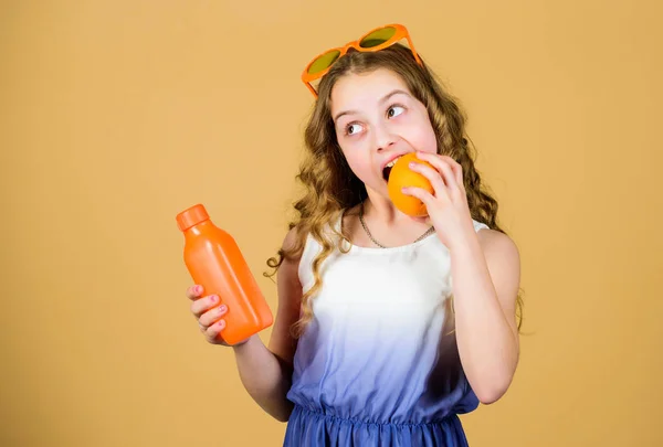 Natural vitamin source. Kid girl eat orange fruit and drink orange juice. Vitamin nutrition. Fashion kid sunglasses drink refreshing vitamin juice. Health care. Summer vitamin diet. Happy childhood