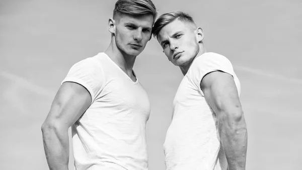Erkek ikiz kas kardeşler gökyüzü arka plan. Yakışıklı güçlü ikizler. Erkekler güçlü kas atlet vücut geliştirmeci güvenle beyaz gömlek poz. Çekici ikizler. Spor yaşam tarzı ve sağlıklı vücut — Stok fotoğraf