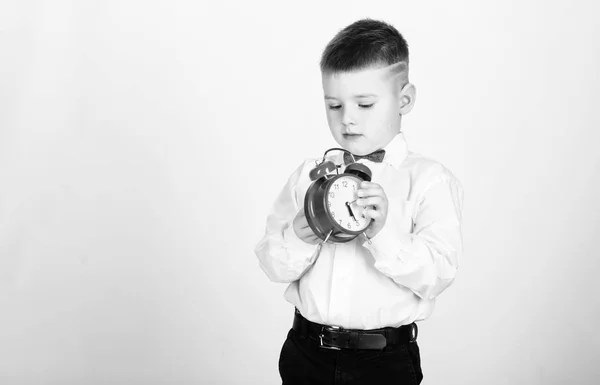 Programação e timing. De manhã. Escolar com despertador. Miúdo adorável menino branco camisa laço vermelho. Desenvolva autodisciplina. Preparar despertador. Criança menino segurar relógio vermelho. Está na hora. — Fotografia de Stock