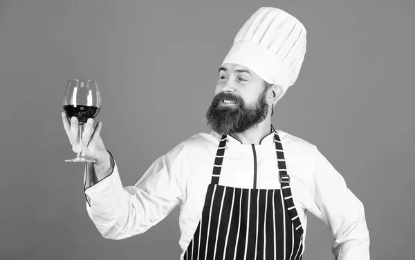 Ausgezeichneter Geschmack. Koch in Kochmütze und Kochschürze verbessern die Fähigkeiten des Sommeliers. Weinausschank im Restaurant. Alkohol trinken. Hipster-Koch hält ein Glas Wein in der Hand. welcher Wein zum Abendessen serviert wird. Sommelier genießen Wein — Stockfoto