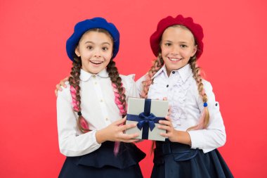 Eğitim vermeye devam eden bir armağandır. Mutlu küçük kızlar pembe arka planda hediye kutusu tutuyorlar. Küçük çocuklar hediye paketi ile gülümsüyor. Güzel sarılmış doğum günü hediye kutusu ile sevimli çocuklar