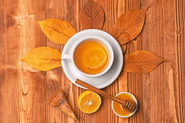 Чашка чая с медом, деревянной ложкой и тортом — стоковое фото