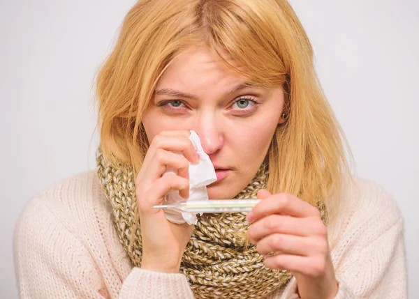 High temperature concept. Take temperature and assess symptoms. Measure temperature. Woman feels badly ill sneezing. Girl in scarf hold thermometer and tissue close up. Cold and flu remedies — Stock Photo, Image