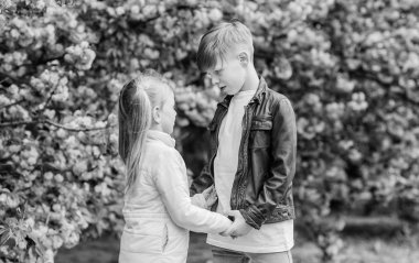 Parkta romantik bir randevu. Aşık olmak için bahar zamanı. Pembe kiraz çiçeğine aşık çocuklar. Havada aşk var. Çift sevimli sevimli çocuklar sakura bahçe yürümek. Şefkatli aşk duyguları. Küçük kız ve erkek