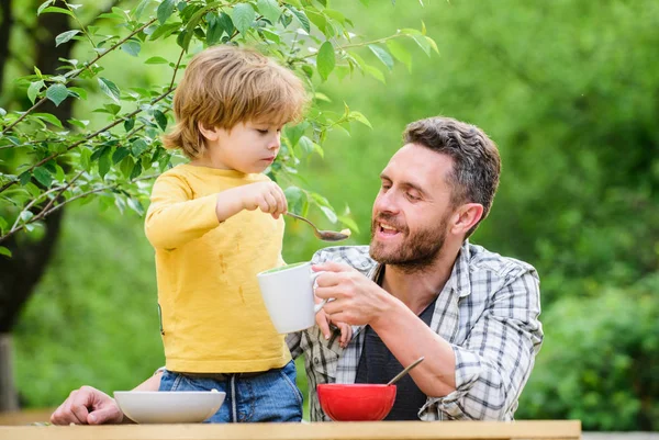 Carefree time together. happy fathers day. Little boy with dad eat cereal. father and son eating outdoor. summer picnic. Morning breakfast. family dinner time. healthy food and dieting. Childrens day — Stock Photo, Image