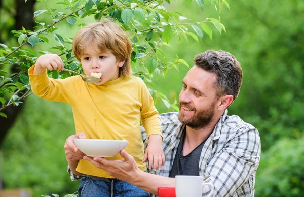 Yemek alışkanlıkları. Babası yla birlikte yiyecek doğa geçmişi yiyen küçük bir çocuk. Yaz kahvaltısı. Sağlıklı gıda kavramı. Bebeği besliyor. Çocuklar için menü. Aile ev yapımı yemeklerin tadını çıkarır. Baba oğul yemek yiyip eğlenir.