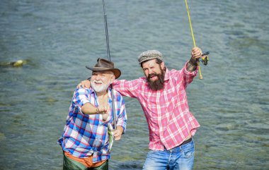 Bağımızı Güçlendirmek Için Toplandık. hobi ve spor aktivitesi. Alabalık yemi. erkek arkadaşlığı. aile bağları. olta ve ağ ile balıkçı. baba ve oğul balık tutuyor. yaz hafta sonu. olgun erkek balıkçı