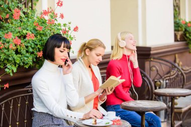 Bilgi kaynağı. Kadın eğlencesi. Hafta sonu rahatlayın ve dinlenin. Farklı ilgi alanları. Hobi ve eğlence. Grup güzel kadın cafe teras konuşma ve dinleme okuma ile kendilerini eğlendirmek