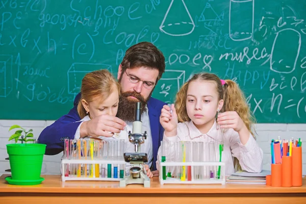 Explaining biology to children. How to interest children study. Fascinating biology lesson. Man bearded teacher work with microscope and test tubes in biology classroom. School biology experiment