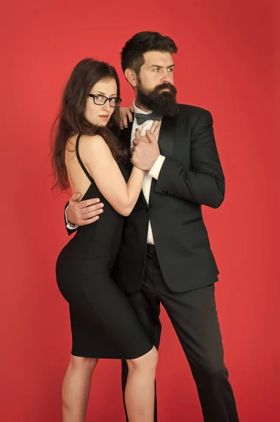 Couple man in tuxedo and elegant girl. Man bearded hipster and woman in formal dress red background. Formal fashion and elegant clothes. Luxury fashion boutique. Fashion clothes shop. Official event
