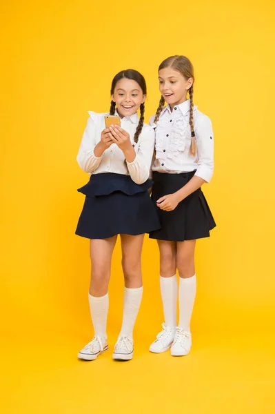 Internet is een prachtige bron, maar de toegang tot het heeft gevaren voor kinderen. Meisjes schooluniform met smartphone. Schoolmeisjes gebruiken mobiele telefoon of smartphone om foto 's te delen. smartphone voor schooltoepassingen — Stockfoto