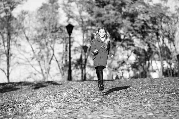 Na podzim oblečení a módní pojem. Dítě blond dlouhé vlasy chůzi padat parku pozadí. Prima v teplé bundě. Dívka šťastný nosit kabát s kapucí krás podzimu. Dítě nosit kabát na podzim — Stock fotografie