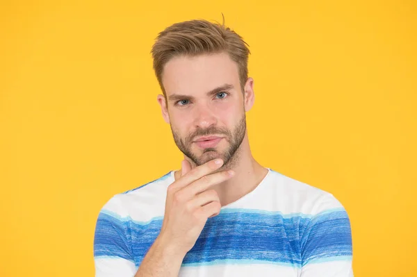 Barbu modérément. Homme barbu sur fond jaune. Un mec non rasé qui touche son menton barbu. Beau modèle caucasien avec moustache et barbe sur le visage barbu — Photo