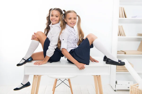 stock image Schoolgirls friends sit on desk. Best friends relaxing. Schoolgirls tidy hairstyle relaxing having rest. School uniform. Rebellious spirit. School club. Little schoolgirls classmates friendly kids