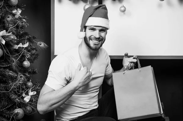 Compras de Navidad en línea. Escena de año nuevo con árbol y regalos. Feliz hombre santo. hombre en sombrero de santa celebrar regalo de Navidad. La mañana antes de Navidad. entrega regalos de Navidad. ¿Estás listo? — Foto de Stock