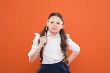 Okul partisi konsepti. Fotoğraf kabini sahne gözlük ile Çocuk akıllı bir görünüm. Sevgililer günü. Kalp aşk sembolü. Turuncu arka planda küçük zeki bir kız öğrenci. Gözlük akıllı stil giyen küçük çocuk