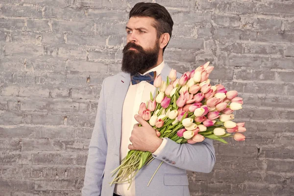 Romantic gift. Macho getting ready romantic date. Tulips for her. Man well groomed tuxedo bow tie hold flowers bouquet. From sincere heart. Things that make man gentleman. Romantic man with flowers