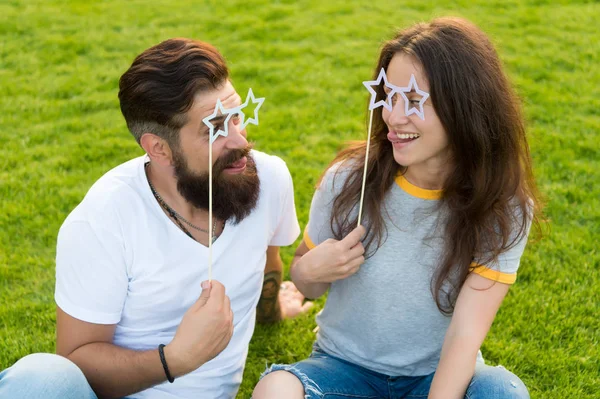 Par i kärlek glada ungdom monter rekvisita. Man skäggiga hipster och vacker kvinna glada ansikten. Ungdomsdagen. Sommarunderhållning. Emotionella människor. Par dating. Bekymmerslöst par ha kul grön gräsmatta — Stockfoto