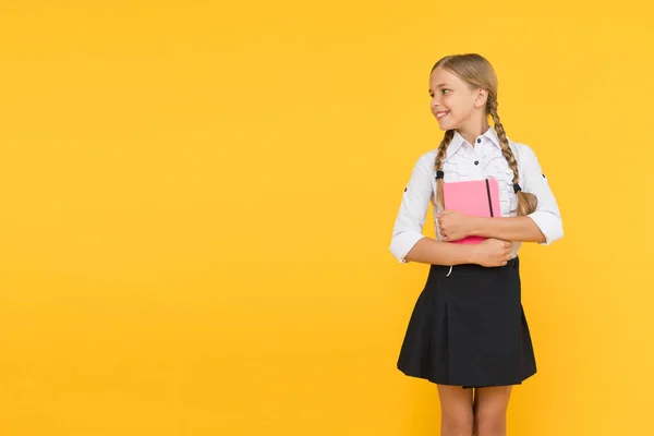 Información escolar. Niño pequeño sosteniendo libro de tiempo con información sobre el fondo amarillo. Una niña tomó un libro de la biblioteca para obtener información. Difundir información y recopilar conocimientos, copiar espacio — Foto de Stock