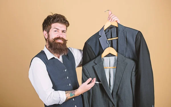 A whole new wardrobe. Wardrobe consultant recommending formal style coats. Hipster choosing suit jacket at wardrobe department store. Bearded man with clothes collection at mens wardrobe — Stock Photo, Image