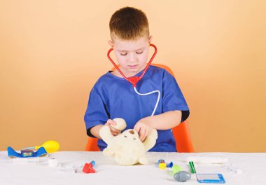 Çocuk sevimli çocuk gelecek doktor kariyer. Sağlık. Çocuk küçük doktor meşgul tıbbi araçlar ile masa. Tıbbi muayene. Tıp kavramı. Oyuncak ayı için tıbbi prosedürler. Tıp eğitimi