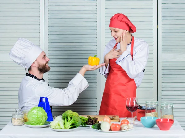 Man chef offer yellow pepper to girl. Just try. Will you eat pepper. Vegetarian family. Woman and bearded man cooking together. Cooking healthy food. Healthy proposal. Join healthy lifestyle