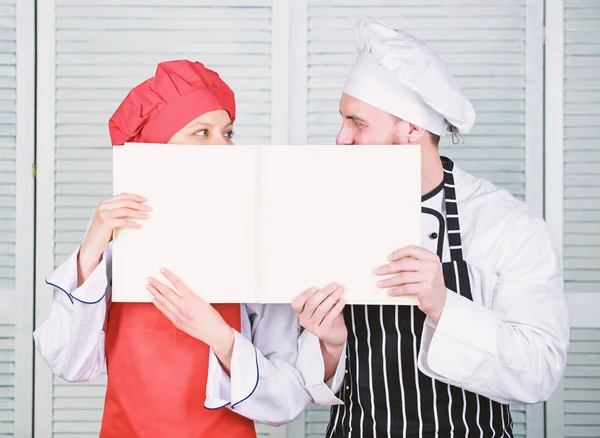 Paperwork. Chef and prep cook holding empty account book. Cook and helper performing book keeping. Couple of man and woman with journal for making records. Book accounting in restaurant, copy space
