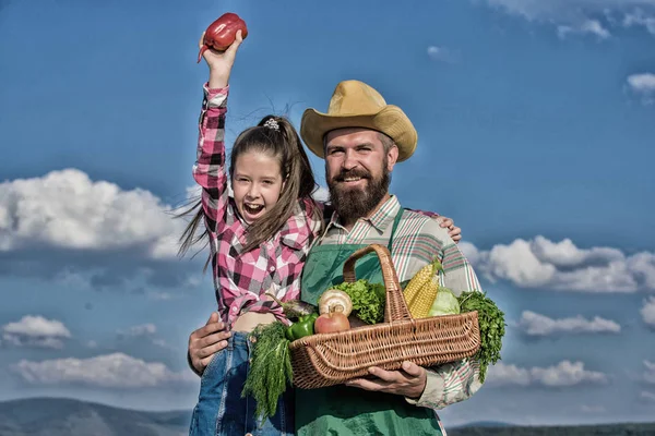 Man bearded rustic farmer with kid. Farmer family homegrown harvest. Only organic and fresh harvest. Father and daughter hold basket harvest vegetables. Gardening and harvesting. Family farm concept
