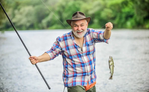 Fish farming pisciculture raising fish commercially. Pensioner leisure. Fisherman alone stand in river water. Hobby sport activity. Fish on hook. Man senior fisherman. Fisherman fishing equipment — Stock Photo, Image