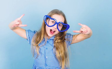 Aşkın gücü. Çocuk kız kalp şeklinde gözlük. Kız sevimli gülümseyen yüz aşık olur. Çocuk büyüleyici gülümseme mavi arka plan. Çocuk mutlu güzel çocukluk keyfini çıkarın. Aşkın kalp sembolü. Moda gözlük