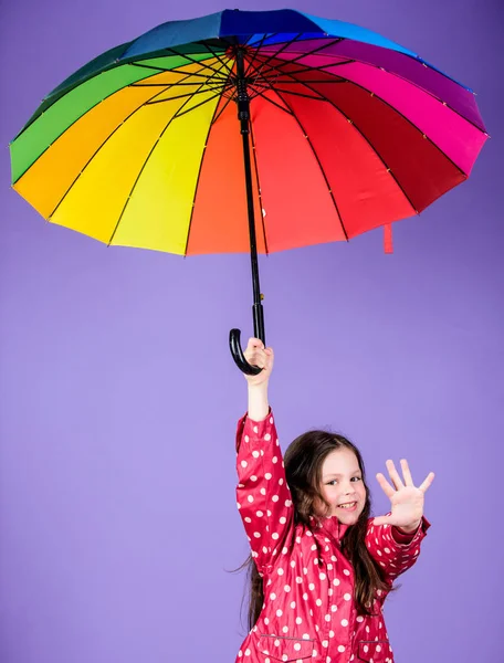 Šťastná procházka pod deštníkem. Užijte si to v dešti. Děvčátko šťastné drží barevný duhový deštník. Deštivé počasí s řádným odětím. Jasný deštník. V něčí oblačnosti buď duha. Deštivá denní zábava — Stock fotografie