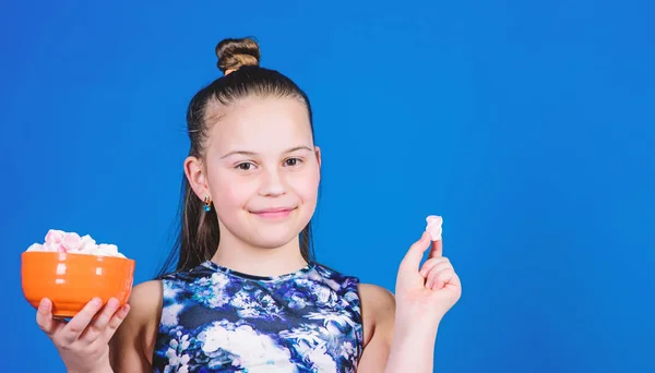 Flicka leende Face Hold skål med söta marshmallows i handen blå bakgrund. Söt och mjuk. Sweet Tooth-konceptet. Kid flicka med långt hår gillar godis och godis. Kalori och diet. Hungrig unge — Stockfoto