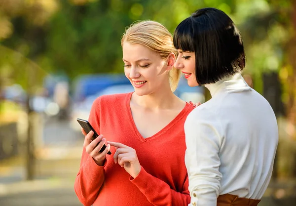 Compra en línea. Dos mujeres con smartphone que se comunican al aire libre. Enlace compartido. Tecnología moderna. Navegar por Internet. Comunicarse en línea. Las chicas se comunican mirando el teléfono. Concepto de redes sociales —  Fotos de Stock