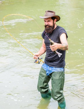 Fisher hafta sonu aktivitesi. Balıkçı ekipmanları ile Fisher. Kancadaki balıklar. Vahşi doğada eğlence. Balık tutmanın eğlencesi yakalamaktır. Balıkçılık erkeksi hobi. Acımasız adam nehir suyunda durmak lastik çizme giymek
