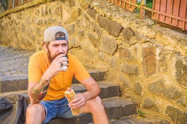 Adam sakallı hızlı atıştırmalık tadını çıkarın. Sokak yemekleri çok güzel. Kentsel yaşam tarzı ve sağlıksız beslenme. Kaygısız hipster merdivenlerde oturup abur cubur yer. Aç adam atıştırması. Abur cubur. Sosisli yiyen adam