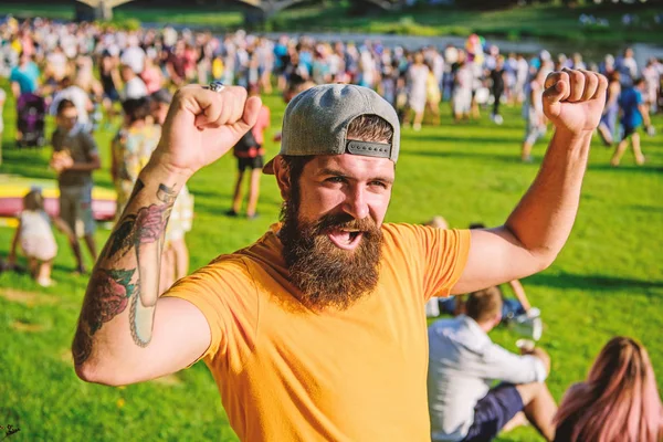 Open air concert. Fan zone. Music festival. Entertainment concept. Visit summer festival. Summer fest. Hipster in cap happy celebrate event fest or festival. Man bearded hipster in front of crowd