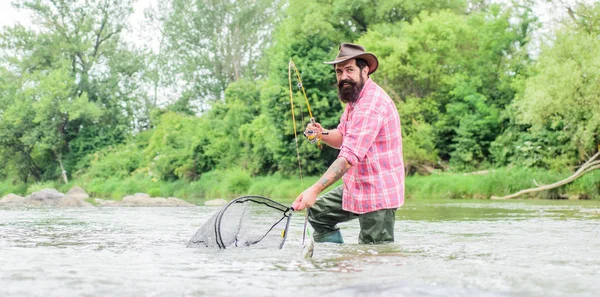 Fishing is astonishing accessible recreational outdoor sport. Bearded fisher catching trout fish with net. Fishing provides that connection with whole living world. Find peace of mind. Fishing hobby